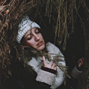 upset woman lying in long grass with hand to chest