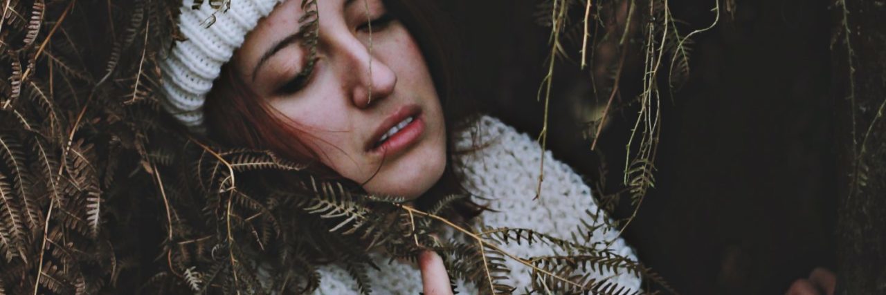 What It's Like to Live With PTSD: A Poem upset woman lying in long grass with hand to chest