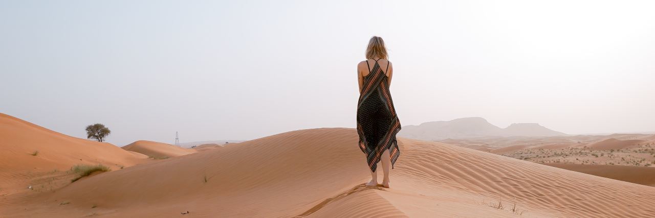 Learning to Honor My Sensory Needs as a Person With Dyspraxia Woman walking alone on the beach.