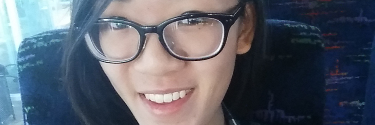 How Having Congenital Heart Disease Has Enriched My Life Melissa Young, Asian-American woman sitting on a bus. Her port and a surgery scar on her chest are visible.