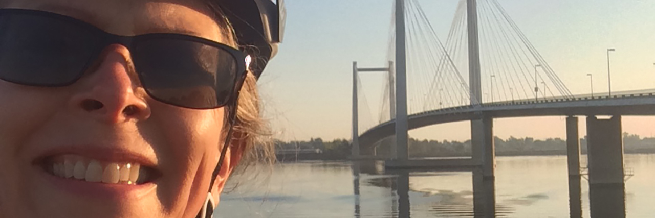 Building Momentum on My Ride With Dystonia Joan Colby wearing a bike helmet on the beach.
