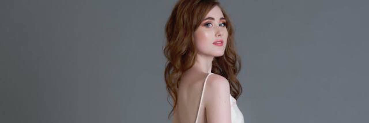 How to Treat People With Gastroparesis and Chronic Illness woman modeling in a white outfit