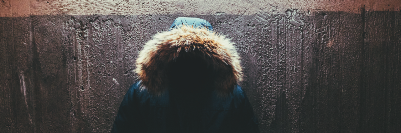 32 Habits of People With Concealed Depression person with hood stands under fluorescent light