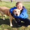 Boy with Down syndrome hugging his brown dog