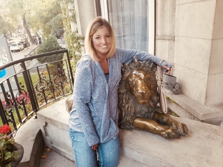 woman sitting on a porch next to a lion statue