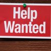 Help Wanted Sign on a wood background.