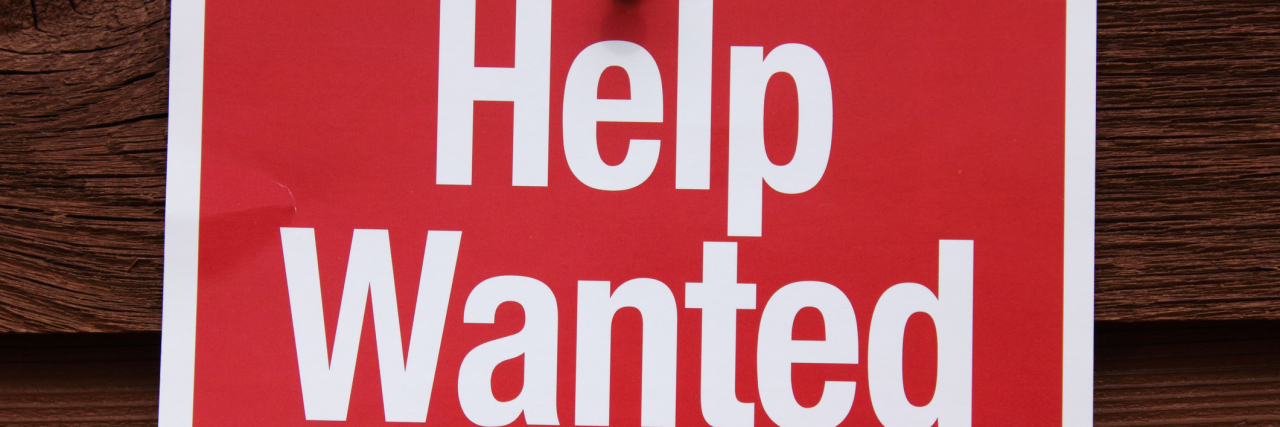Help Wanted Sign on a wood background.