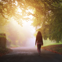A solitary woman walking on a country road.