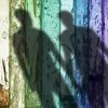 Shadow of two gay men on a rainbow weathered fence.