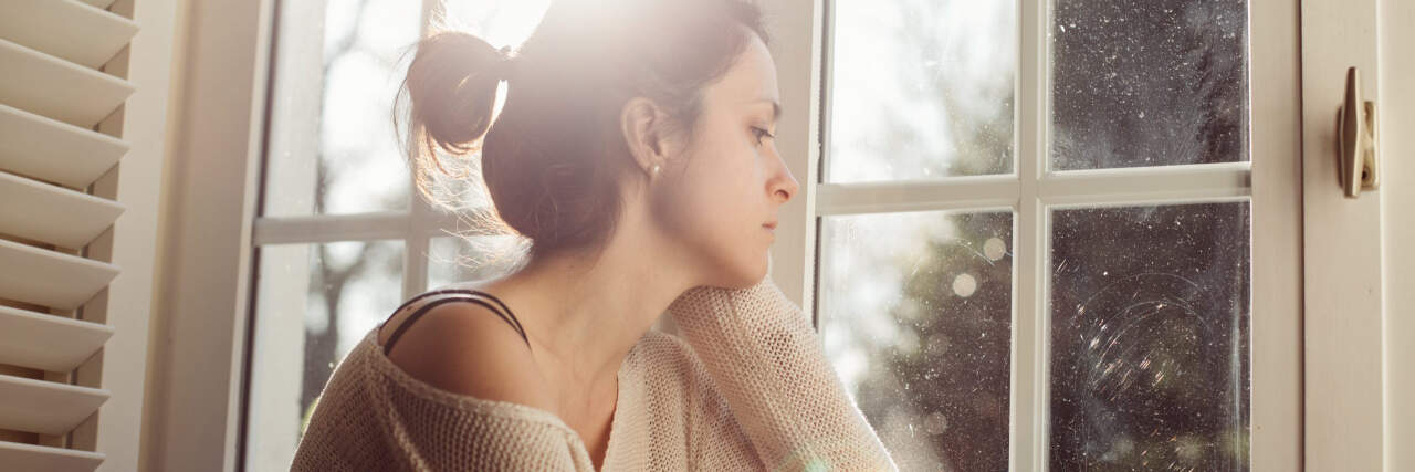 woman looking sad in front of a window