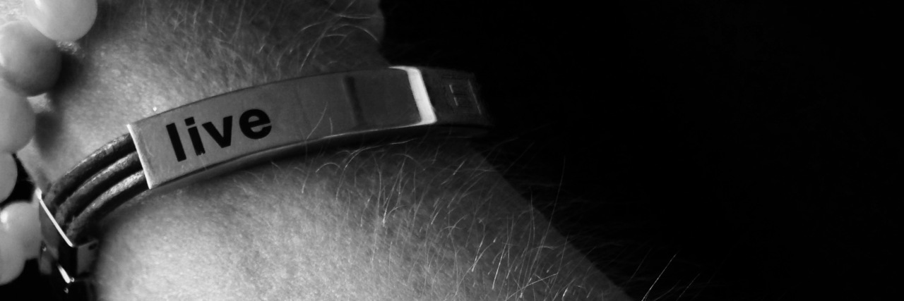 The Positive Effects of Lupus on My Relationships black and white photo of a woman's arm with a bracelet that says 'live' and an IV in her arm