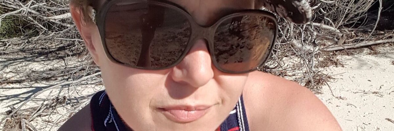 woman sitting on the beach in a hat and sunglasses