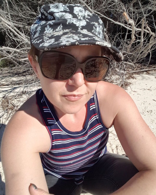 woman sitting on the beach in a hat and sunglasses