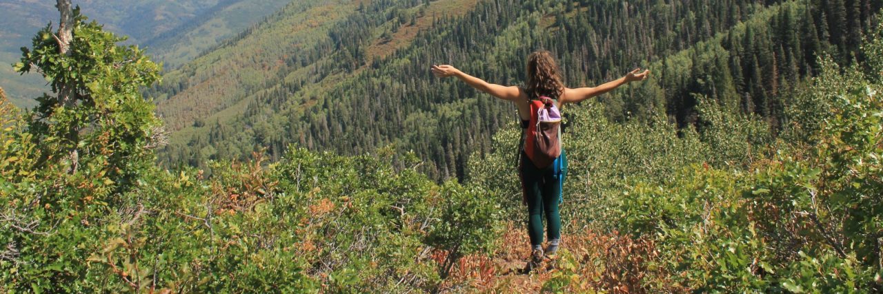 How Nature Saved My Life in Drug Addiction Recovery woman standing in mountains with arms outstretched
