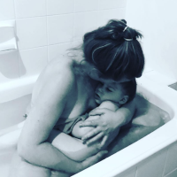 Mother holding child inside a tub