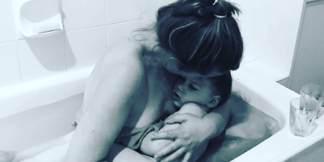 Mother holding child inside a tub