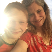 Mother and son smiling at camera with sun shining bright on them
