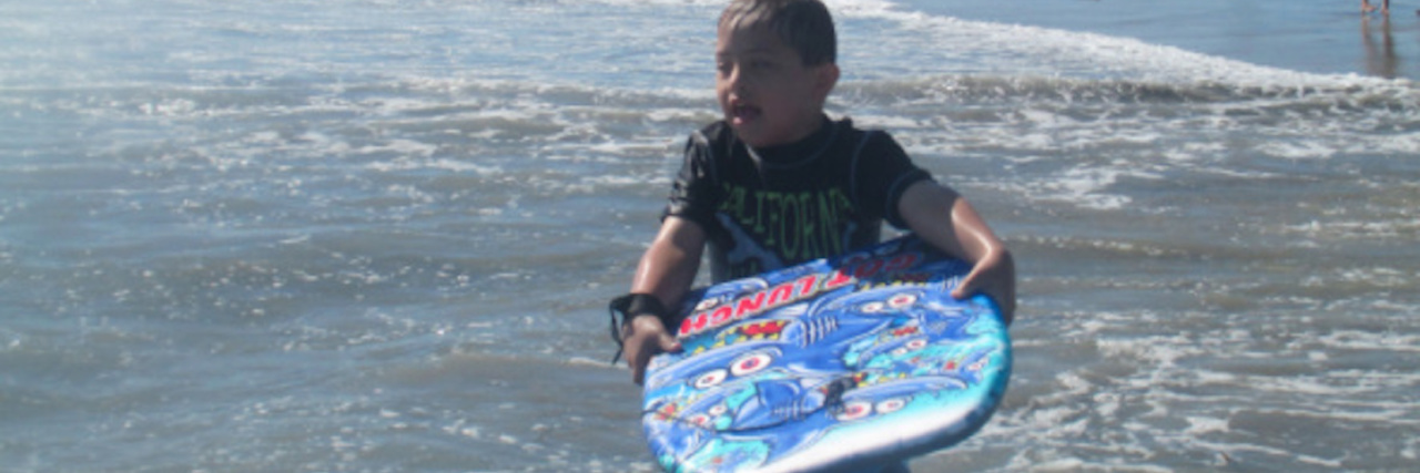 My Most Helpful Supporters in the Down Syndrome Community The author's son, holding a boogie board while in the ocean near the shore