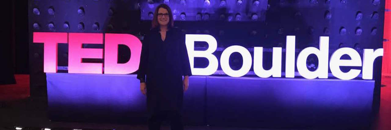 How I Began to Heal From 20 Years of Back Pain kate nicholson in front of TEDxBoulder sign