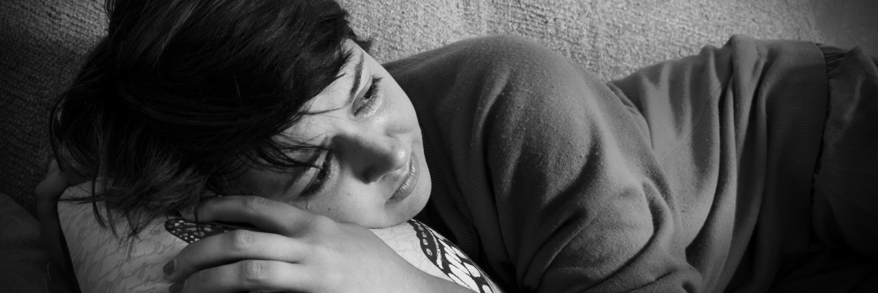 3 Things You Can Do When Mental Illness Makes You Sensitive to Touch A depressed young woman lying on a couch in black and white