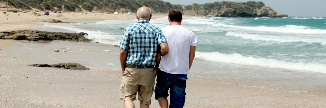 Portrait of adult son and father walking on beach