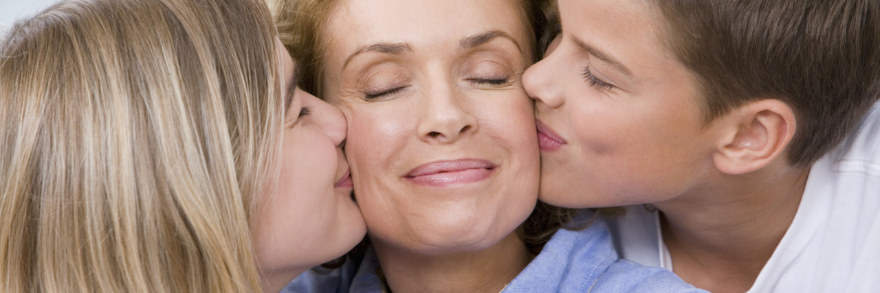 mother being kissed on her cheeks by her daughter and son