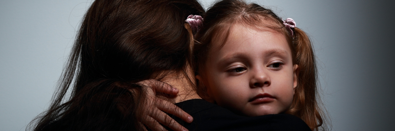 Parenting as Someone With Dissociative Identity Disorder Small sad daughter hugging her mother with love on dark background