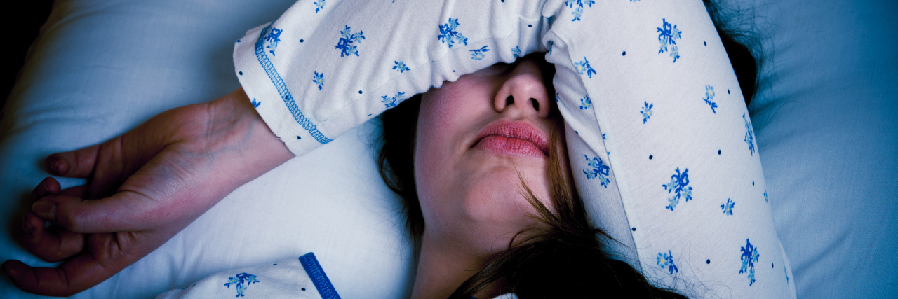 What a Weekend Is Like With Migraine woman lying in bed with her arm covering her eyes