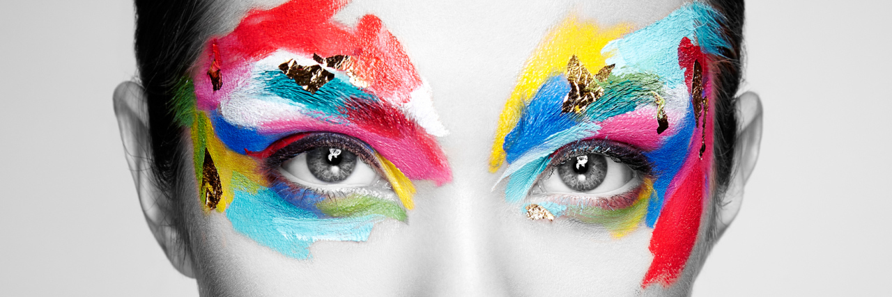 black and white photo of woman with colorful makeup around her eyes