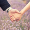 husband and wife holding hands in front of a field of flowers