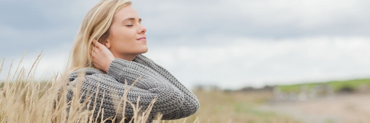 Letting Go of Old Dreams Due to Idiopathic Intracranial Hypertension woman sitting outside in the grass smiling with her eyes closed