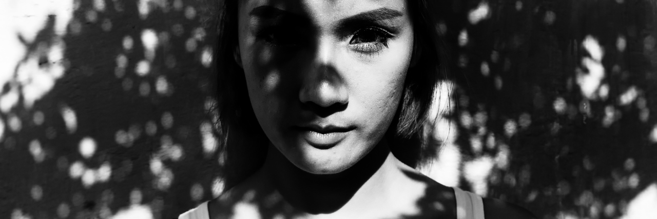 What Living With Chronic Pain Has Taught Me woman standing in the shadows of trees