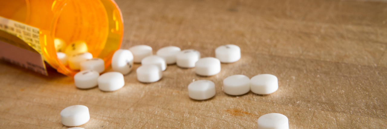 White pills spilling onto a wooden table.