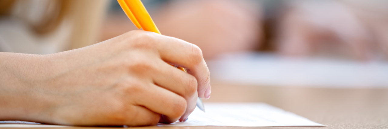 Responding to People Who Don't Believe I Have ADD Student writing on paper at desk in classroom