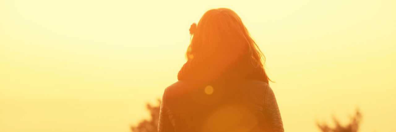 My Double Life as a Brain Injury Survivor Woman wearing jacket, walking, facing sunset