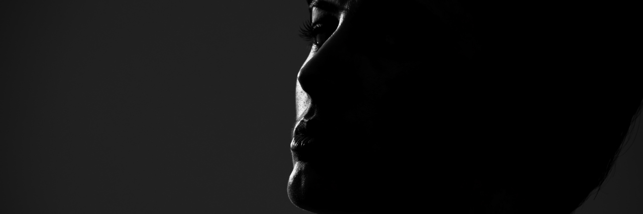 How I'm Living Through My 'Dark Days' With Mental Illness Back lit low key portrait of short hair woman looking at camera