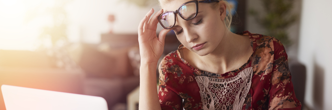 How to Stay Organized and Get Back on Track After a Pain Flare woman sitting at her desk with a computer looking stressed