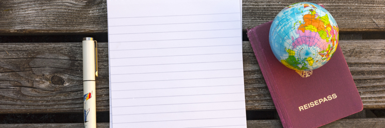 My Chronic Illness Bucket List After Rheumatoid Arthritis Diagnosis pad of paper next to a passport and mini globe