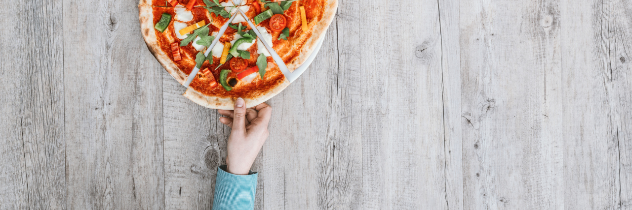 What Eating Pizza Means to My Binge Eating Disorder Recovery Friends sharing a delicious pizza on a rustic table, they are holding a slice, top view