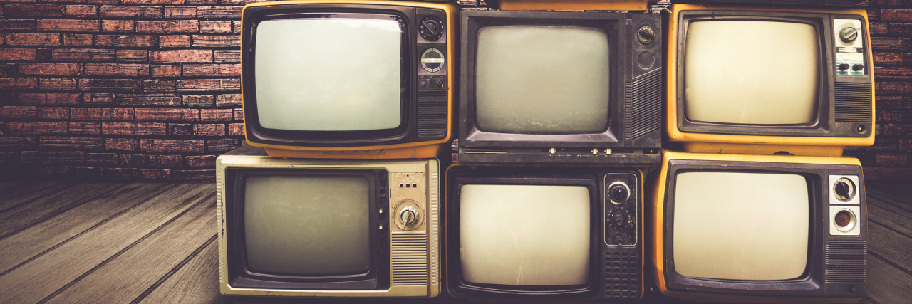 Why People Get Upset By Illness Misrepresentation in the Media Vintage style TVs stacked on one another, in front of a brick wall.