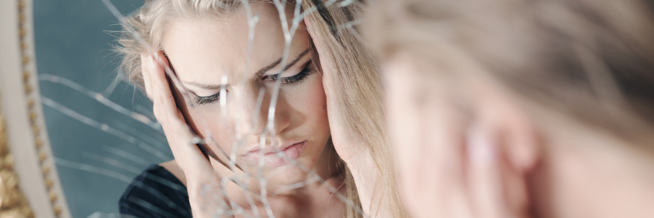What You Need to Understand About My Dissociative Identity Disorder girl's reflection looking distraught or upset in broken mirror