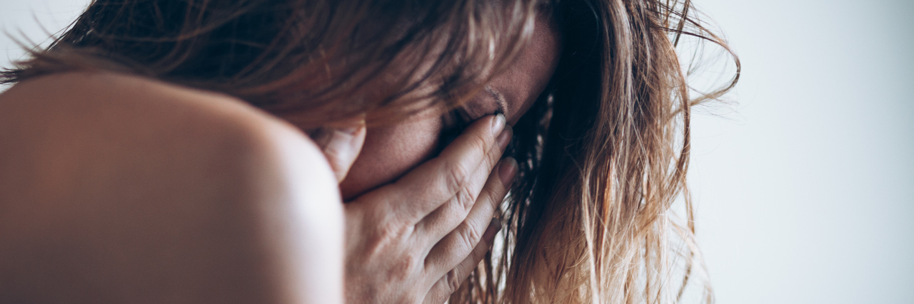 The Most Unexpected and Scary Symptom of My Postpartum Depression young woman screaming crying with hands covering eyes