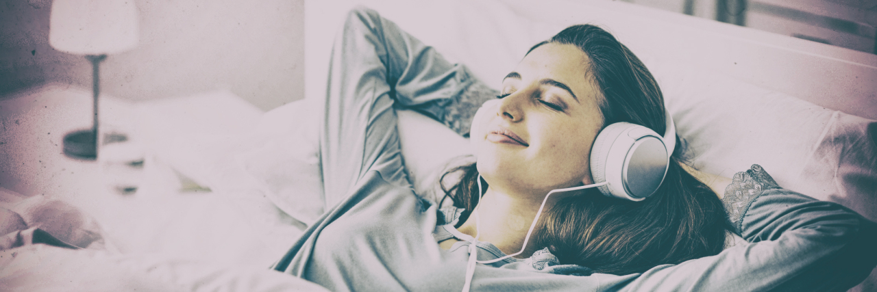 Finding Hope Through Music After Traumatic Brain Injury Woman listening to headphones in bed.