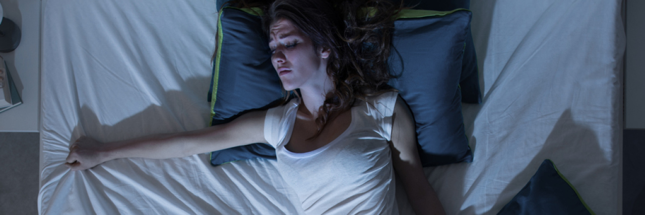 When Anxious Nighttime Thoughts Make You Feel Alone Nervous woman suffering from insomnia and lying in bed late at night, she is awake and restless, top view