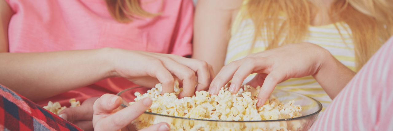 Young women eating popcorn watching movie.