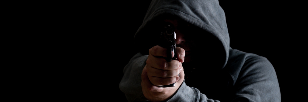 Why Equating Violence With Mental Illness Is Problematic Man in green hoodie points gun