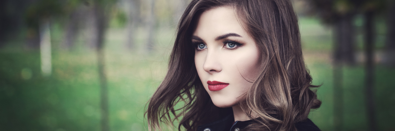 Can We Treat Eating Disorders and Gastroparesis Together? A young woman outside with a serious look on her face, as she looks away from the camera.