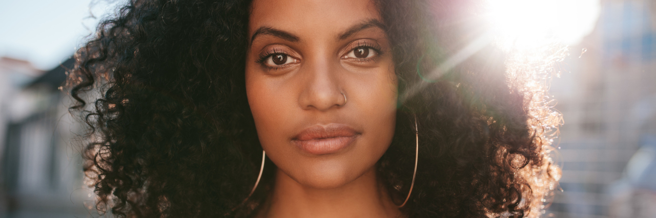 What 'I'm Hanging in There' Means for Someone With Chronic Illness woman with curly hair standing outside