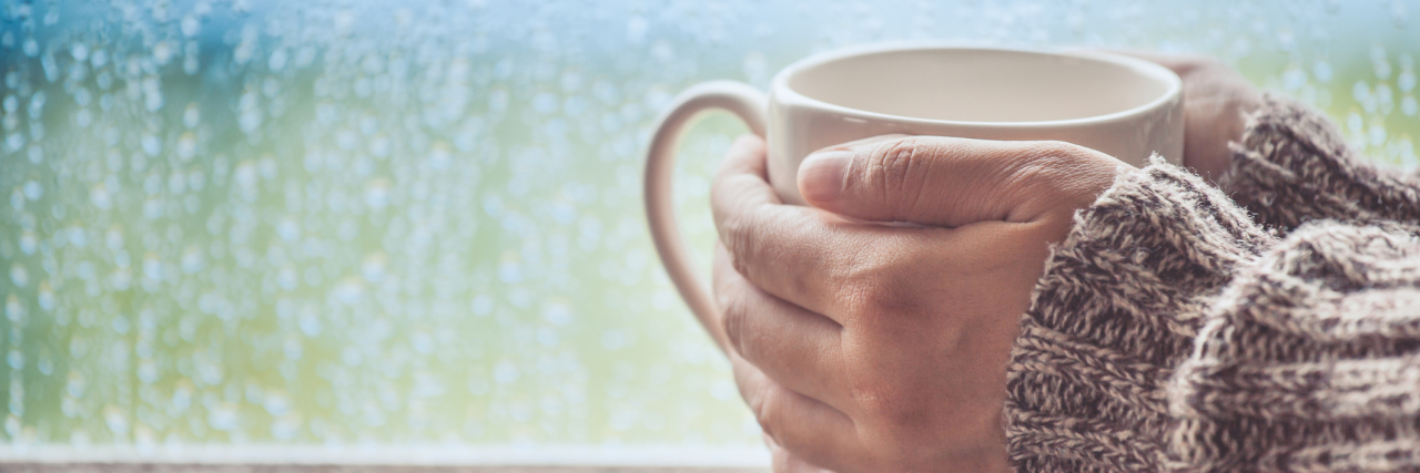 My Values for Life With Fibromyalgia woman holding a mug of tea on a rainy day