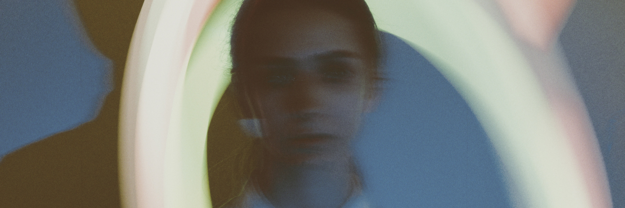 When Depression Battles OCD, and Anxiety Becomes the Middle Man woman blurred with blurry lights in the background
